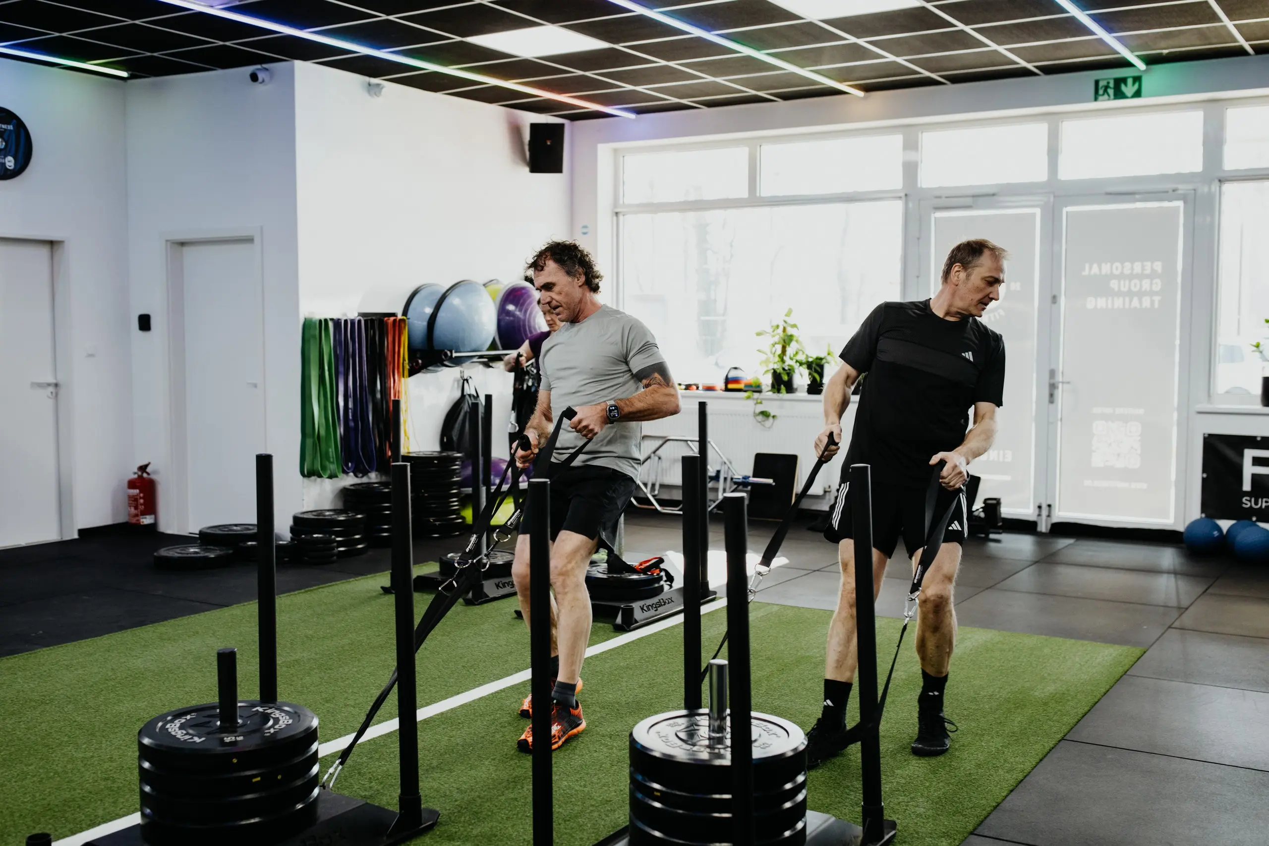 Zwei Mitarbeiter trainieren gemeinsam an den Schlitten im HM Fitness Studio